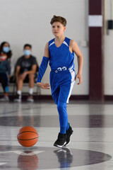 Young athletic boy playing in a game of basketball