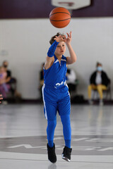 Young athletic boy playing in a game of basketball