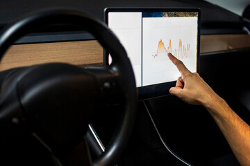 Male technician examining graph on digital tablet while programming in car