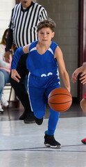Naklejka premium Young athletic boy playing in a game of basketball