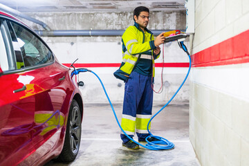 Male technician charging electric car at auto repair shop