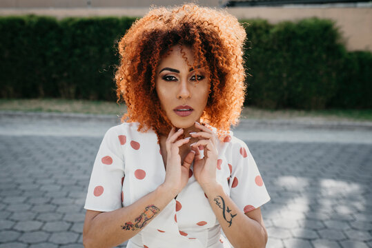 Confident woman with hand in hair standing on footpath