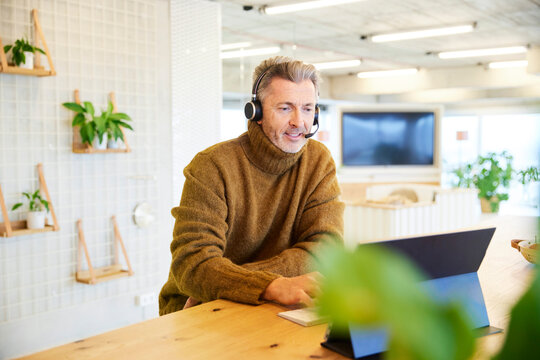 Businessman with headset talking while using digital tablet at office