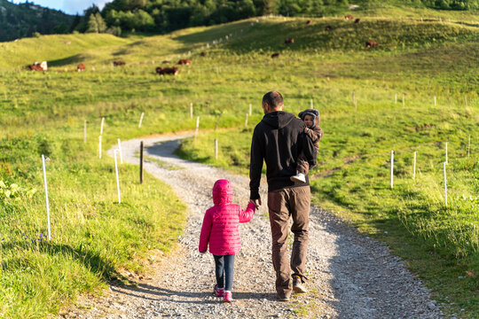 Father walking with two children on walkway of Col des Aravis, Haute-Savoie on sunny day, France