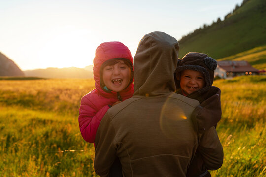 Mother with cheerful two children in agricultural field at sunset during vacations at Col Des Aravis, Haute-savoie, France