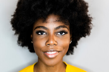 Close-up of woman smiling while standing against white background