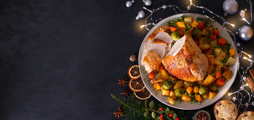 Roasted turkey breast with potatoes, carrots, turnip and brussel sprouts. Christmas dinner table with decorations. View from above, copy space