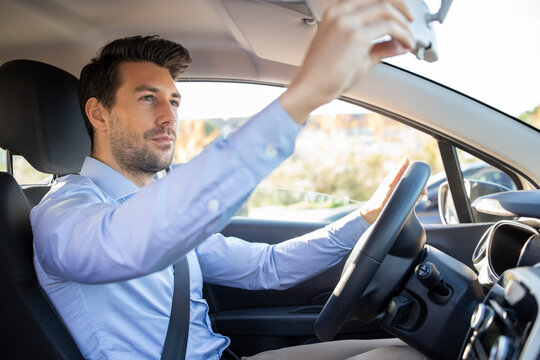 Fototapeta Businessman adjusting rear view mirror while sitting in car