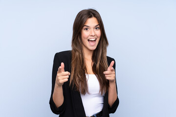 Young Brazilian business woman over isolated blue background points finger at you