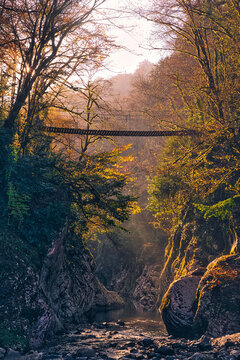 Suspension bridge stretching over&not;&dagger;Khosta&not;&dagger;River flowing through Devils Gate canyon at sunset