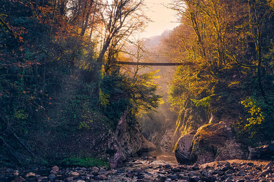 Suspension bridge stretching over Khosta River flowing through Devils Gate canyon at sunset
