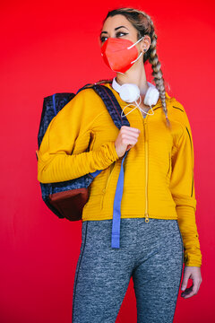 Female athlete wearing face mask looking away while standing against red wall
