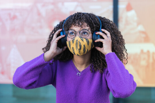 Afro woman listening music through headphones during COVID-19