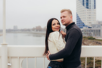 A young couple in sweaters cuddles on the bridge