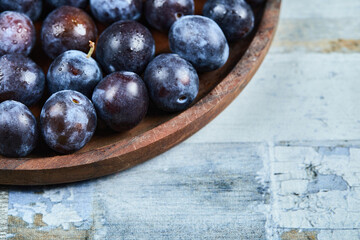Garden plums in a plate on a blue background