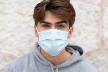 Young man wearing protective face mask against wall during coronavirus