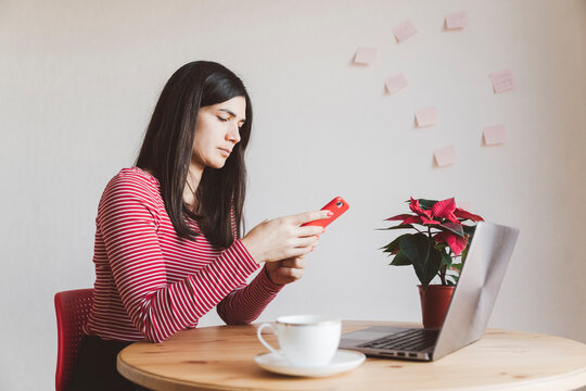 Woman with laptop using mobile phone while sitting at home office