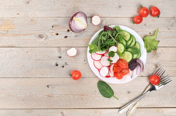 Green vegetable salad with cherry tomatoes, cucumber, radish and fresh arugula, detox diet. Healthy...