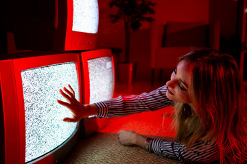 Young woman touching vintage TV screen while lying on front at home