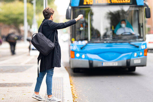 Young man hailing bus from footpath in city