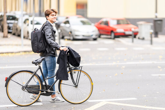 Smiling young man walking with bicycle on street in city