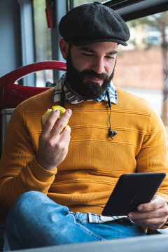 Smiling businessman using digital tablet while having fruit in bus