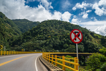 Car parking prohibited sign on a bridge at a curve on a rural highway in Colombia