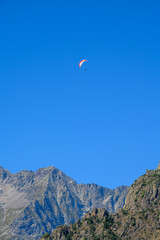 Paraplaners in tandem gliding in blue sky and Alpine mountains on paraplane
