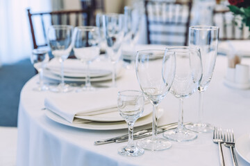 Fancy table set for dinner with napkin glasses in restaurant, luxury interior background. Wedding elegant banquet decoration and items for food arranged by catering service on white tablecloth table.