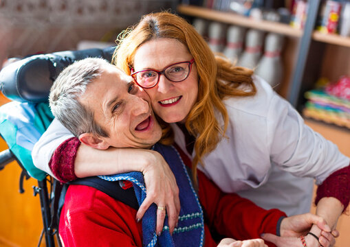 Smiling female healthcare worker embracing disabled man at rehabilitation center
