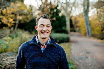 Smiling mid adult man standing in front of trees in public park