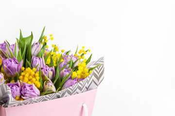 Bouquet of lilac tulips and yellow mimosas in pink box on white background, copy space, side view. March 8, February 14, birthday, Valentine's, Mother's, Women's day celebration, spring concept