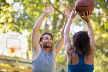 woman against a man couple playing basketball