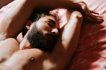 Shirtless man relaxing on bed