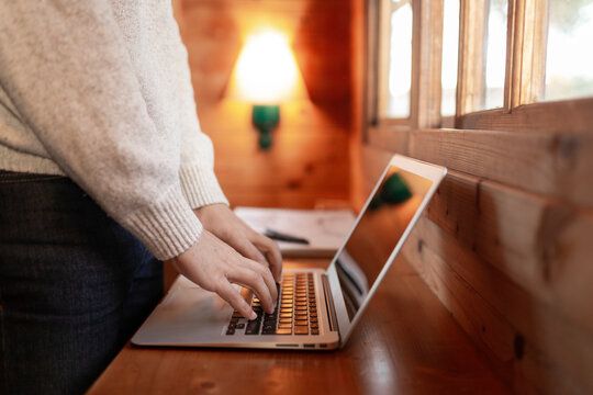 Young man using laptop on wooden table in log cabin
