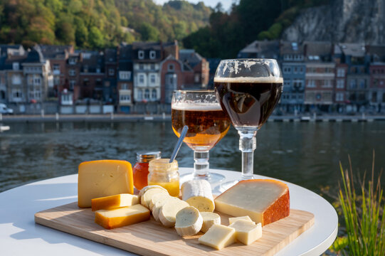 Glass of Belgian abbey beer and tasting of cheeses made with trappist beer and fine herbs with view on Maas river in Dinant, Wallonia, Belgium
