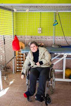 Mature disabled woman sitting on wheelchair exercising with rope at rehabilitation center