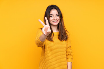 Young caucasian woman isolated on yellow background smiling and showing victory sign