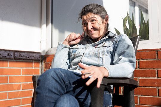 Smiling disabled woman making face while sitting on chair outside nursing home