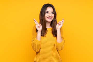 Young caucasian woman isolated on yellow background with fingers crossing