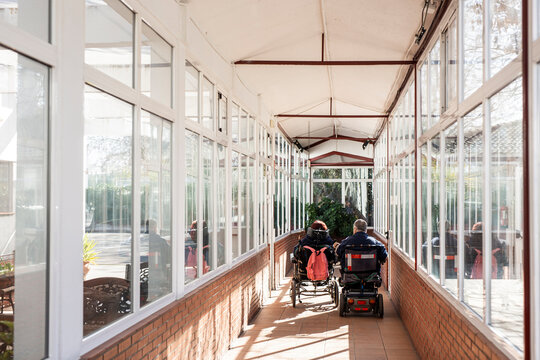 Disabled male and female on wheelchair in corridor at nursing home