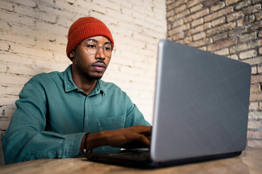 Businessman working on laptop against brick wall at table