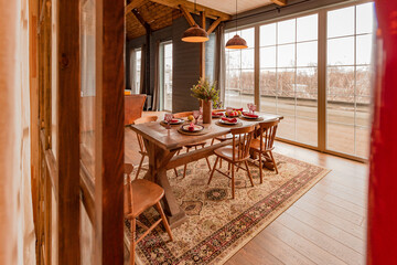 cozy all wooden interior of a country house in a wooden design. spacious living room with kitchen area with large windows. bedroom on the second floor.