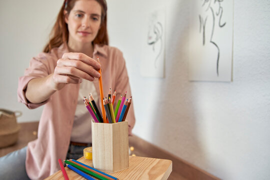 Female artist choosing colored pencil while working at home