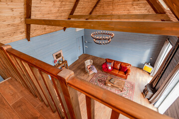 cozy all wooden interior of a country house in a wooden design. spacious living room with kitchen area with large windows. bedroom on the second floor.