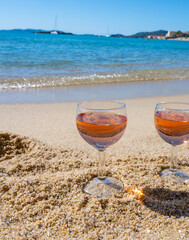 Two glasses of local rose wine on white sandy beach and blue Mediterranean sea on background, near Le Lavandou, Provence, France