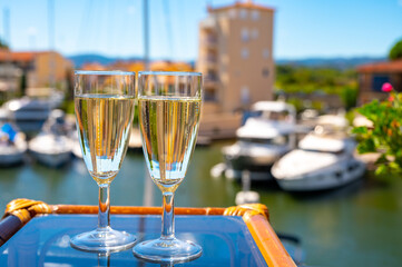 Summer party with sparkling champagne wine and sail boats haven of Port Grimaud on background, Provence, France