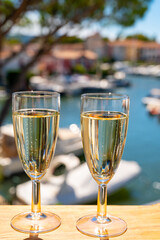 Summer party with sparkling champagne wine and sail boats haven of Port Grimaud on background, Provence, France