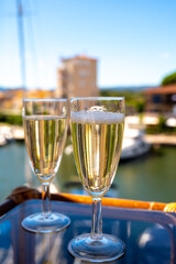 Summer party with sparkling champagne wine and sail boats haven of Port Grimaud on background, Provence, France