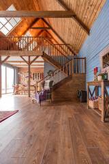 cozy all wooden interior of a country house in a wooden design. spacious living room with kitchen area with large windows. bedroom on the second floor.
